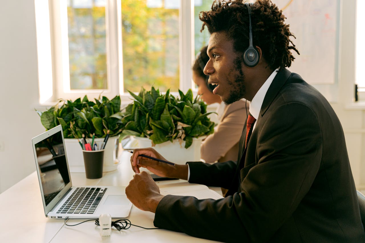 Professional African American man with afro hair working at laptop in office setting.